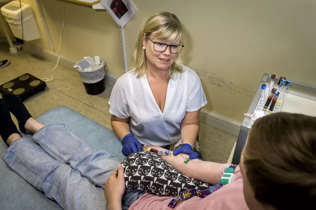 Photo of a research nurse who takes a blood sample from one of the participants in a screening study.